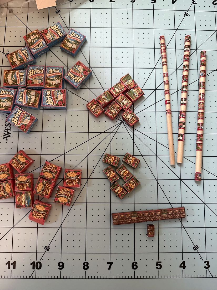 Can labels wrapped around three wooden dowels next to finished miniature boxes
